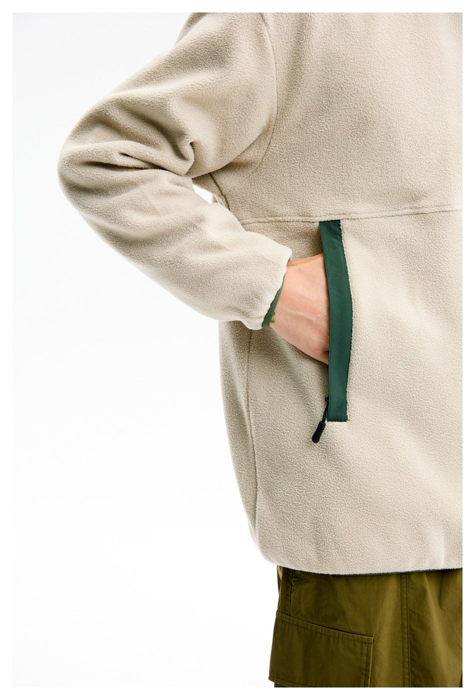 Close-up of the cream fleece pullover's dark green-trimmed vertical zip pocket and sleeve cuff.