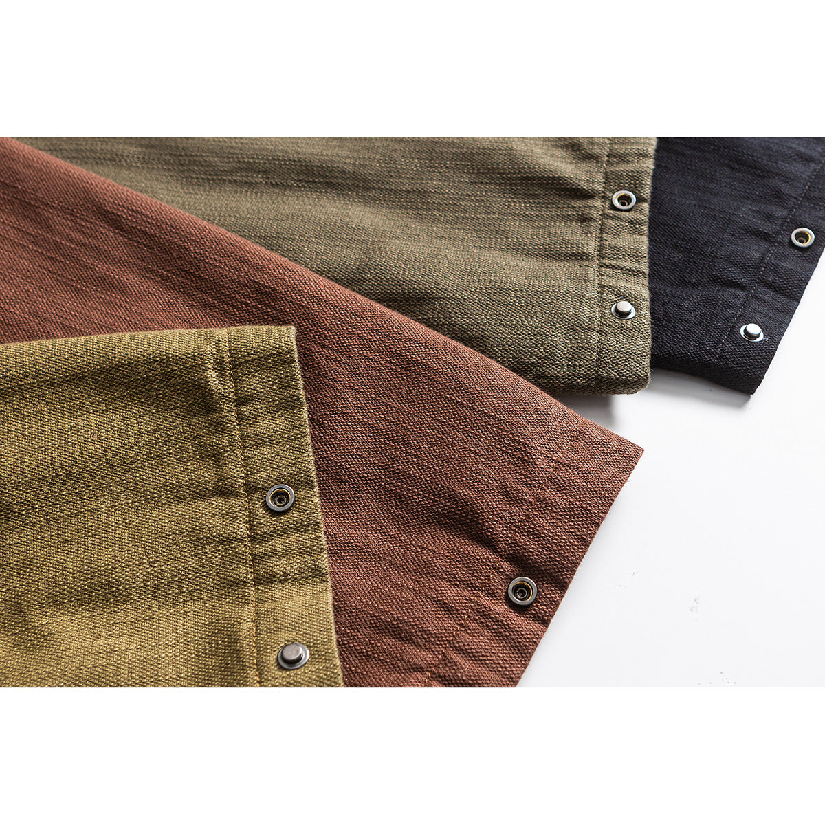 Close-up of olive, rust-brown, and black jacket cuffs with metal snap fasteners.