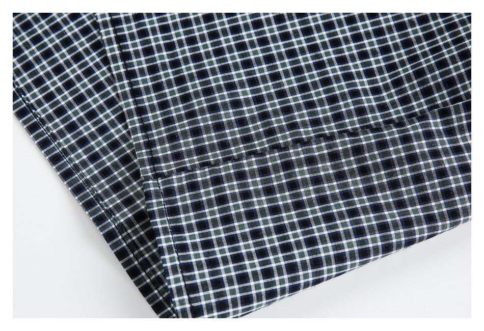 Close-up of the checked shirt's lower hem and stitched seams on a white background.
