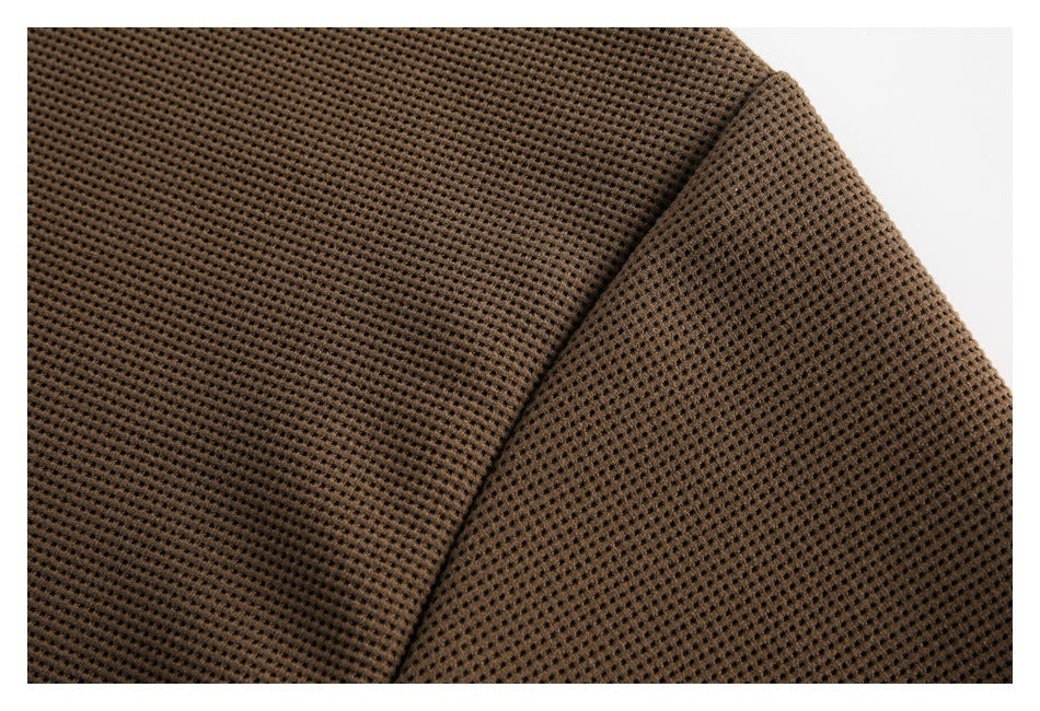 Close-up of a curved seam across brown waffle-knit fabric.