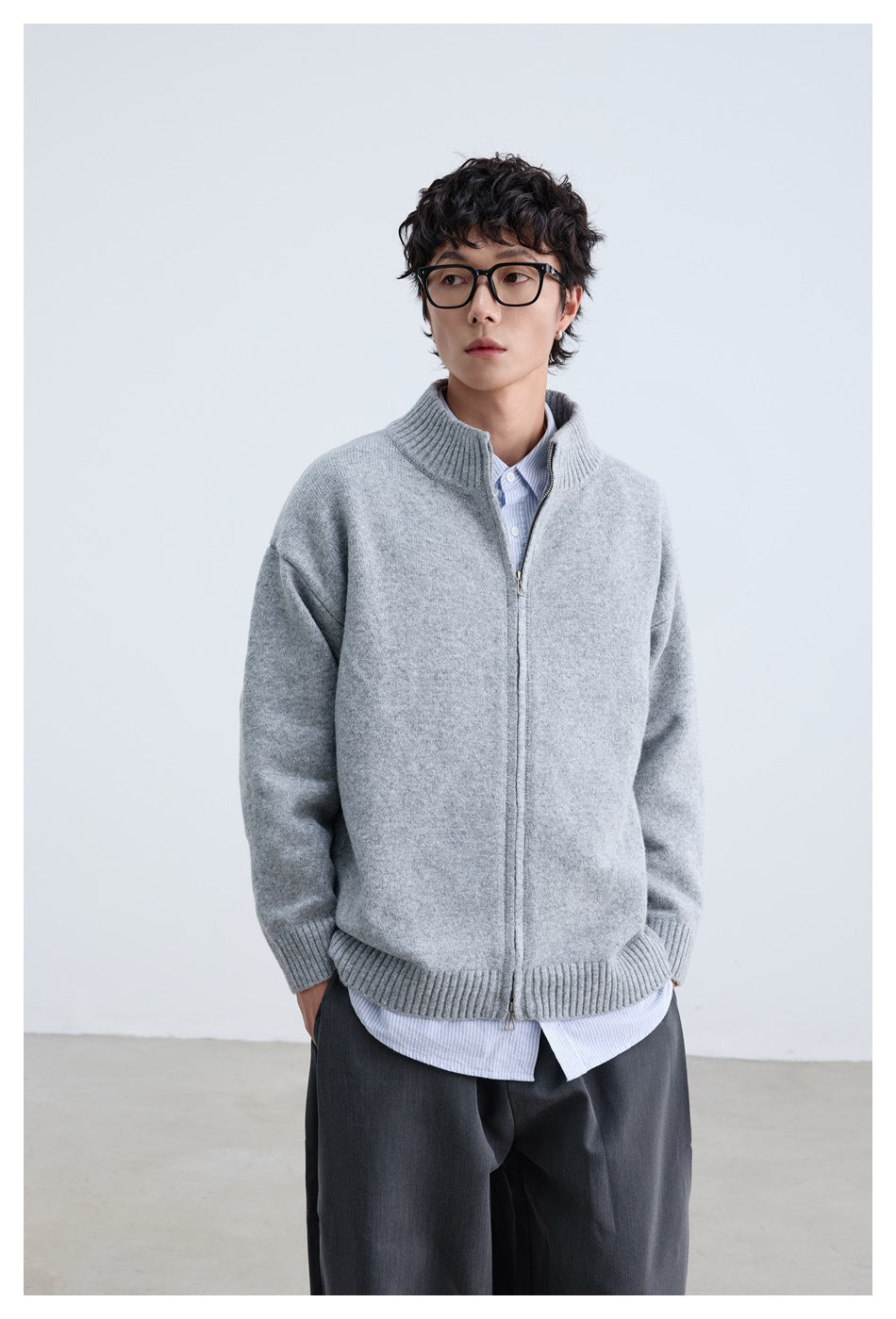 Front view of a model wearing a light gray zip-front cardigan with ribbed trim and a striped shirt.