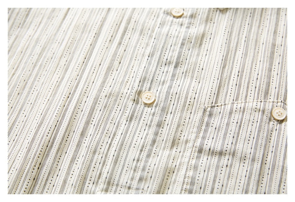 Close-up of the ivory shirt’s button placket and chest pocket, with fine black dotted stripes.