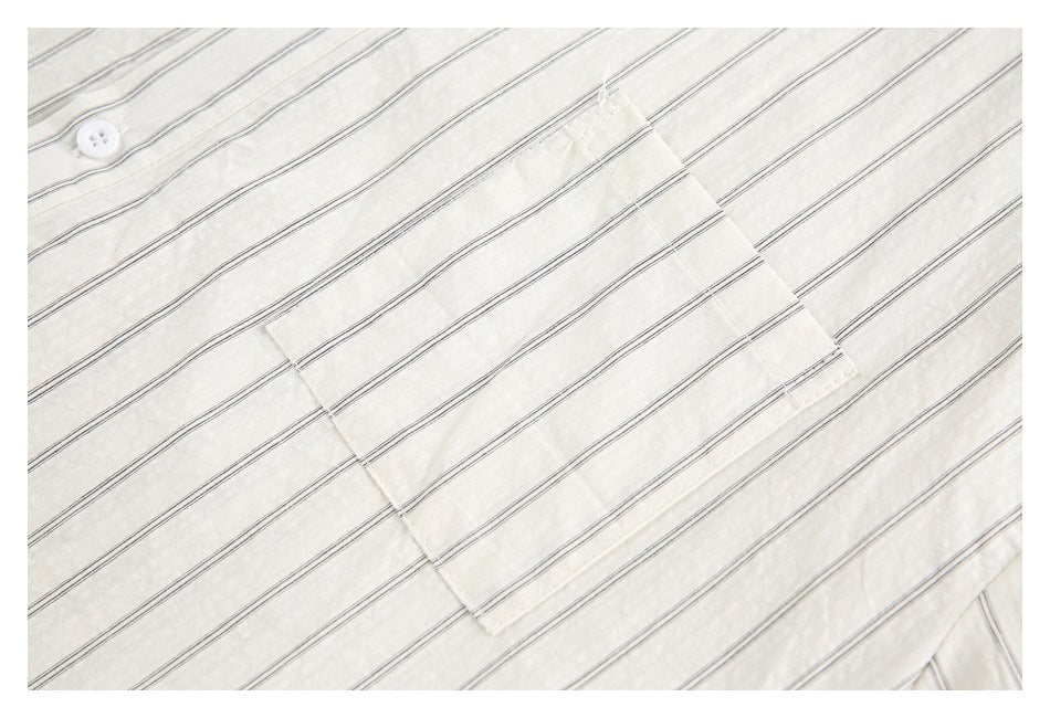 Close-up of a rectangular patch pocket on an ivory shirt with thin dark stripes.