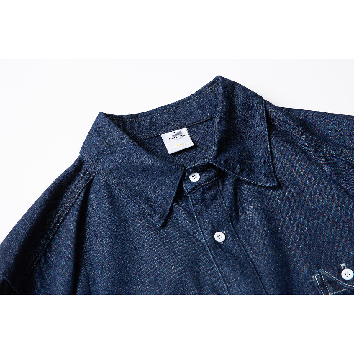 Close-up of a dark indigo button-up shirt showing its pointed collar, white buttons and part of the chest pocket.