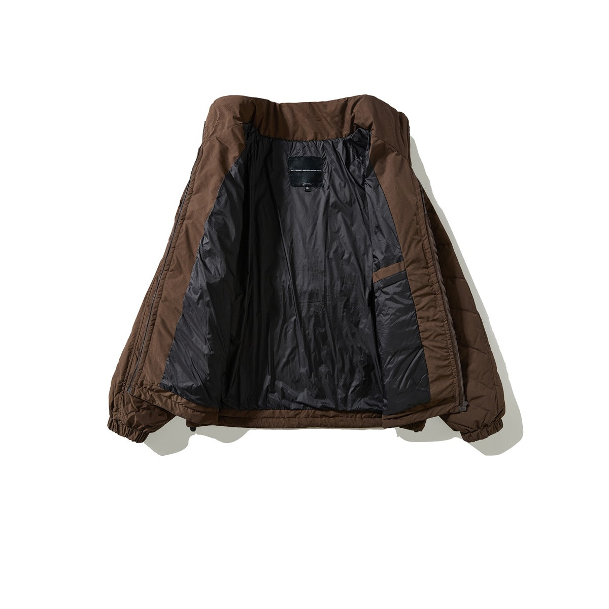 Brown quilted jacket opened to show its dark lining, inner pocket, and neck label.