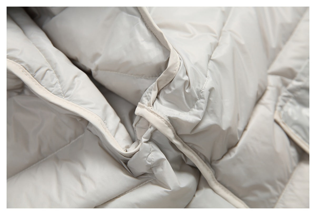 Close-up of the pale gray jacket's quilted panels and cream-colored bound seam.