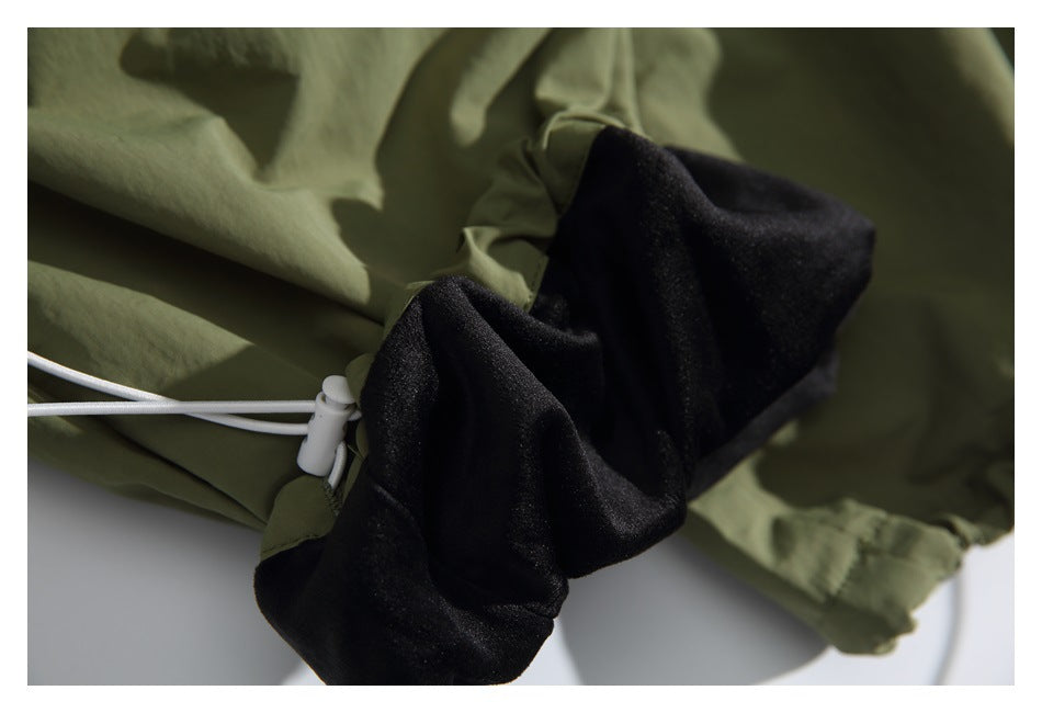 Close-up of olive-green shorts with a white drawcord and exposed black inner fabric.