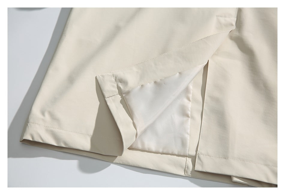 Close-up of a cream garment hem with a folded vent and visible stitching.