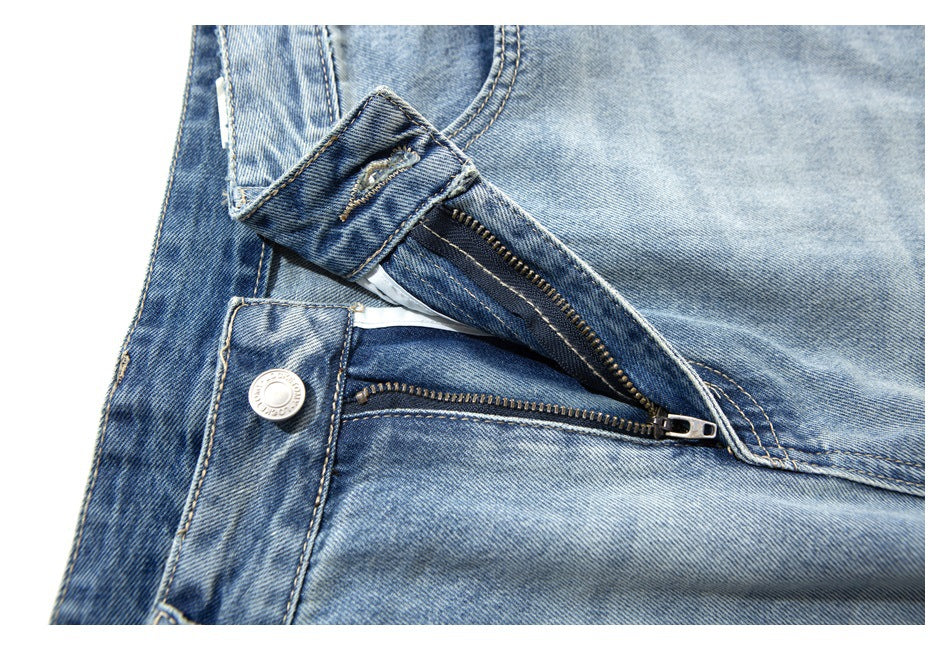 Close-up of light blue jeans with the waistband unfastened, showing the metal button and zipper fly.