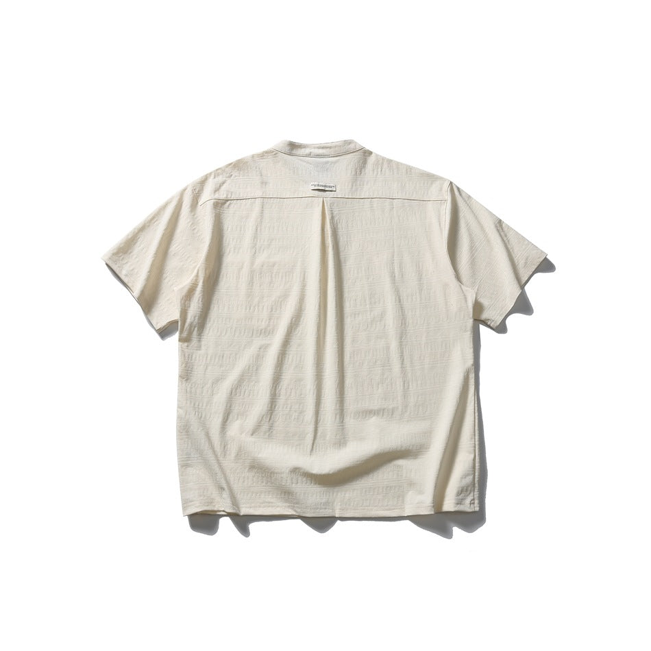 Back view of an off-white short-sleeve band-collar shirt with subtle horizontal texture and a center pleat.