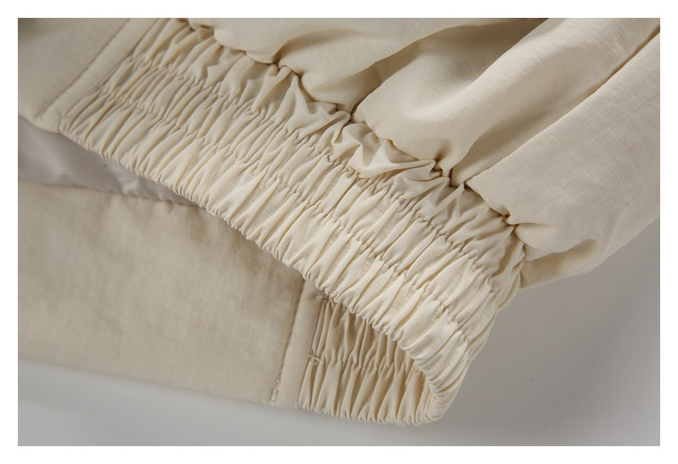 Close-up of the cream jacket's gathered elastic hem.