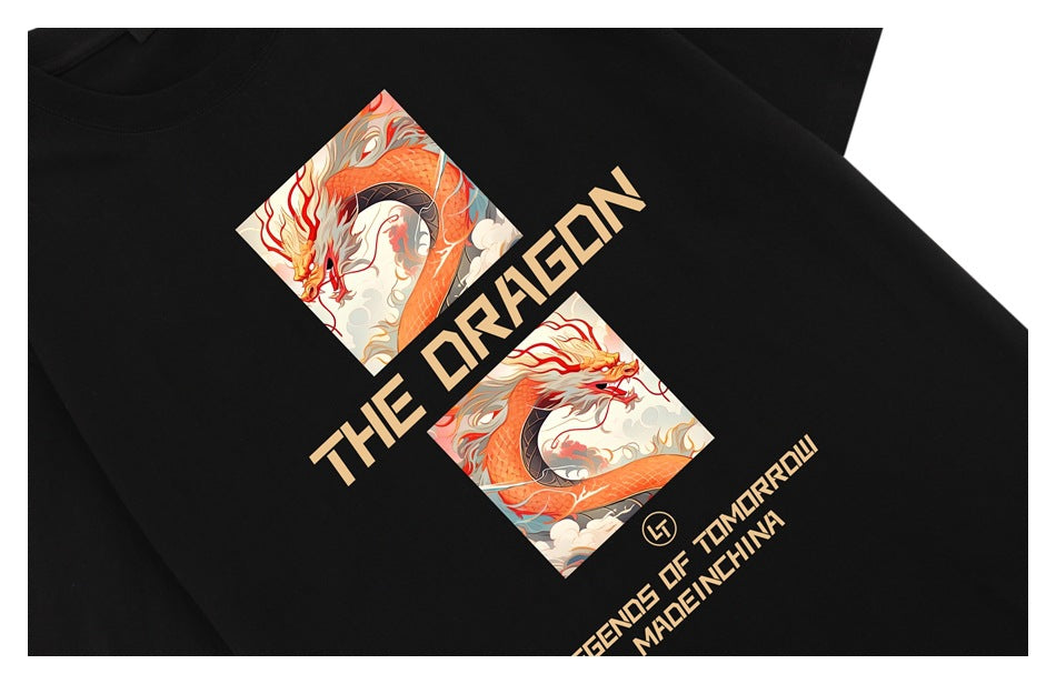 Close-up of a black T-shirt with orange dragon artwork and tan English lettering.