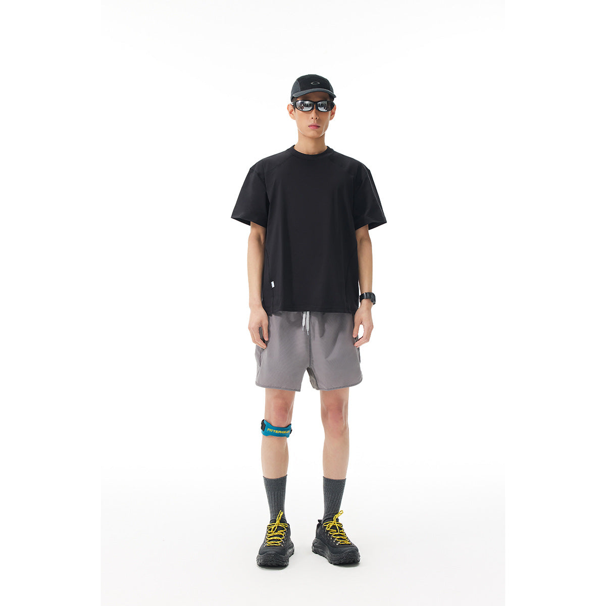 Full-length model wearing a plain black short-sleeve T-shirt and gray shorts against a white background.