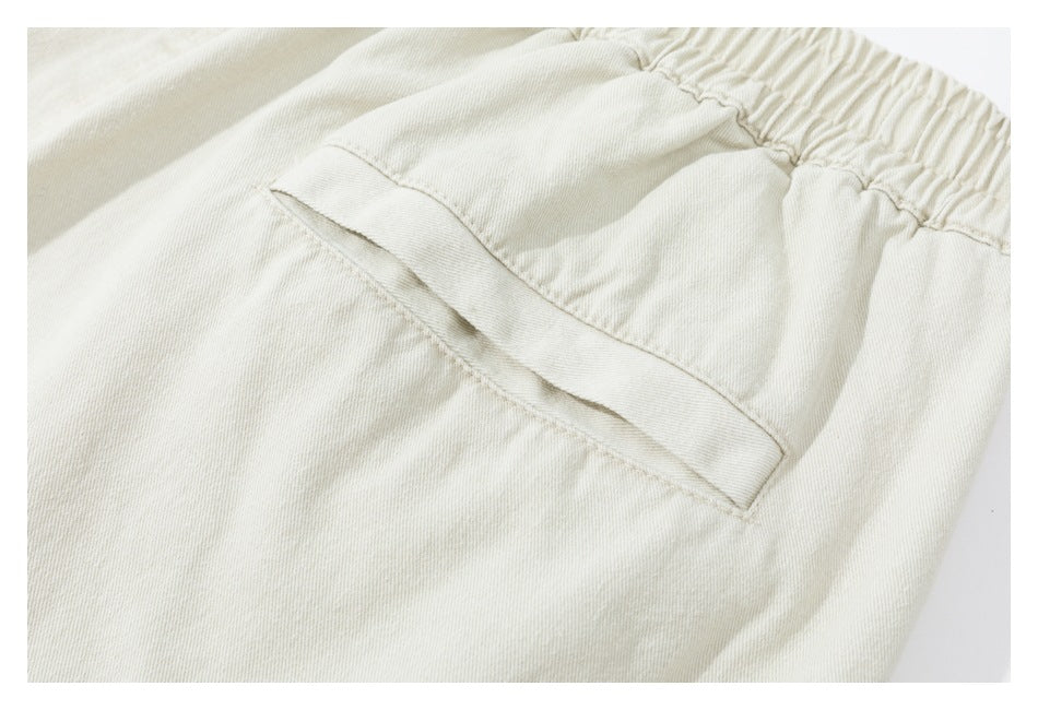 Close-up of a slanted pocket beneath the elastic waistband of light beige trousers.