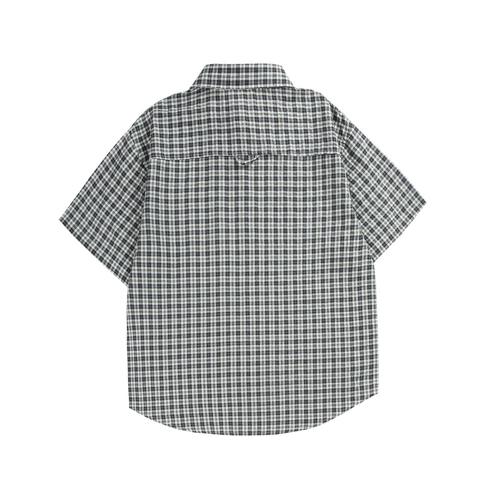 Back view of a short-sleeve collared shirt in black, white, and gray plaid on a white background.