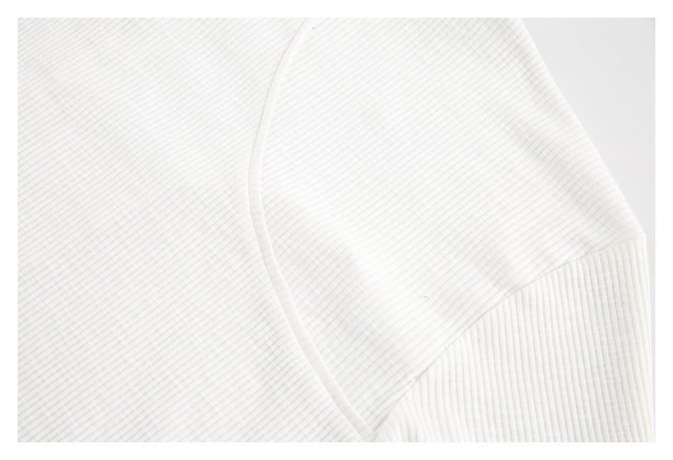 Close-up of an ivory rib-knit garment showing a curved seam and a contrasting ribbed panel.