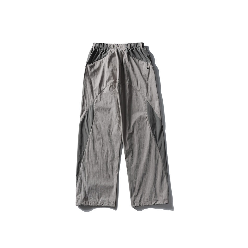 Front view of light gray wide-leg pants with an elastic waist, angled pockets, and darker gray contrast panels.