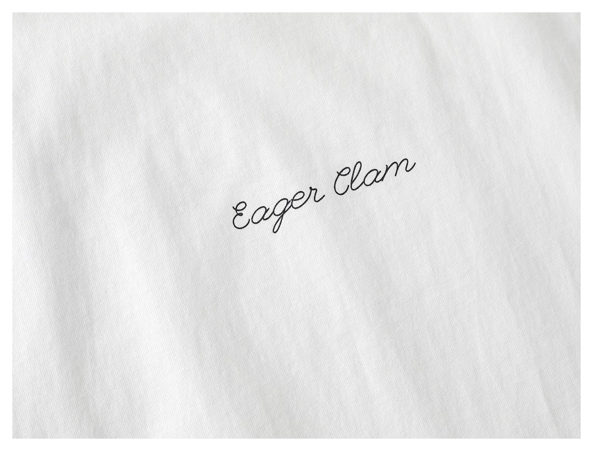 Close-up of a white shirt with small black cursive “Eager Clam” lettering.