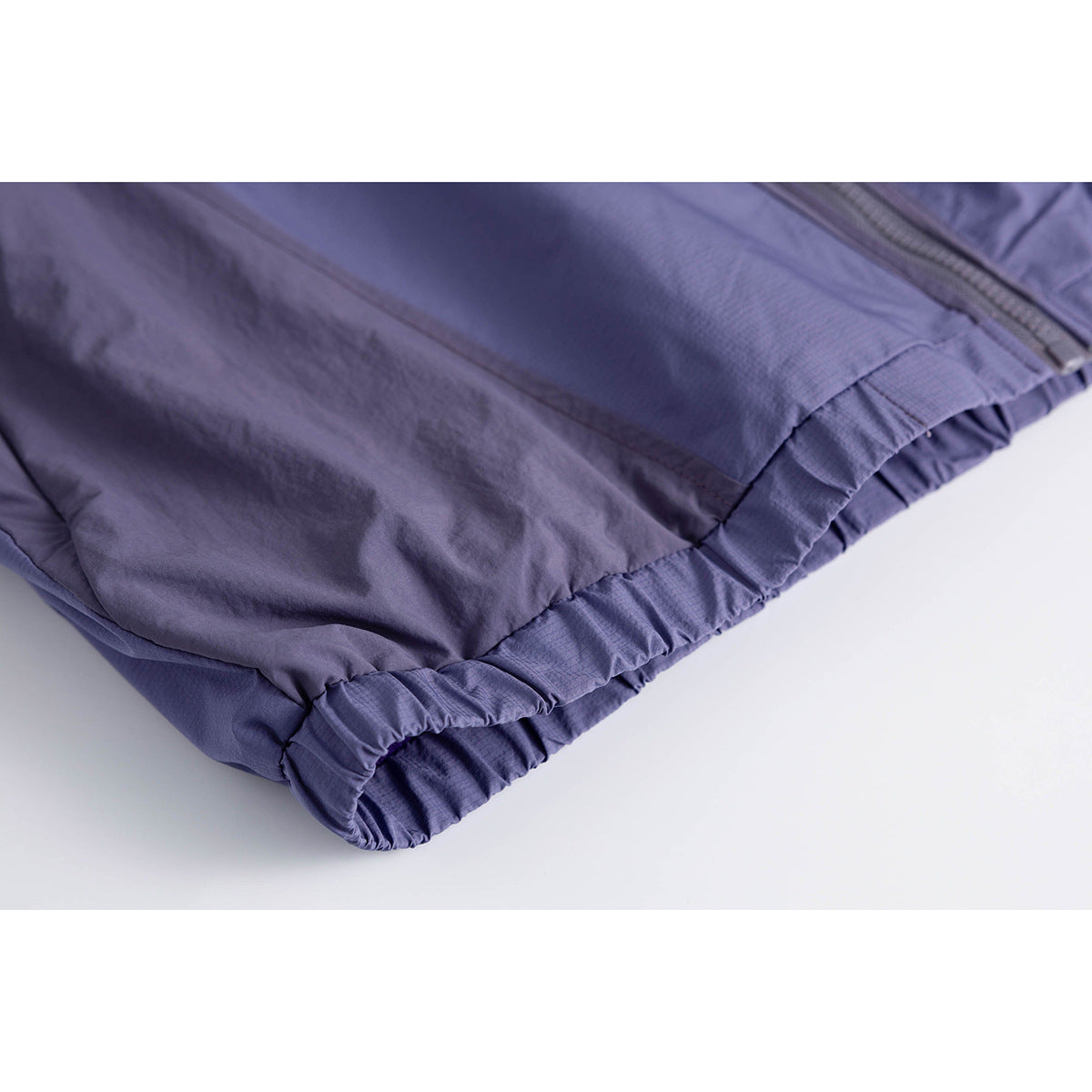 Close-up of the blue-violet jacket's elasticized hem and lower front zipper.