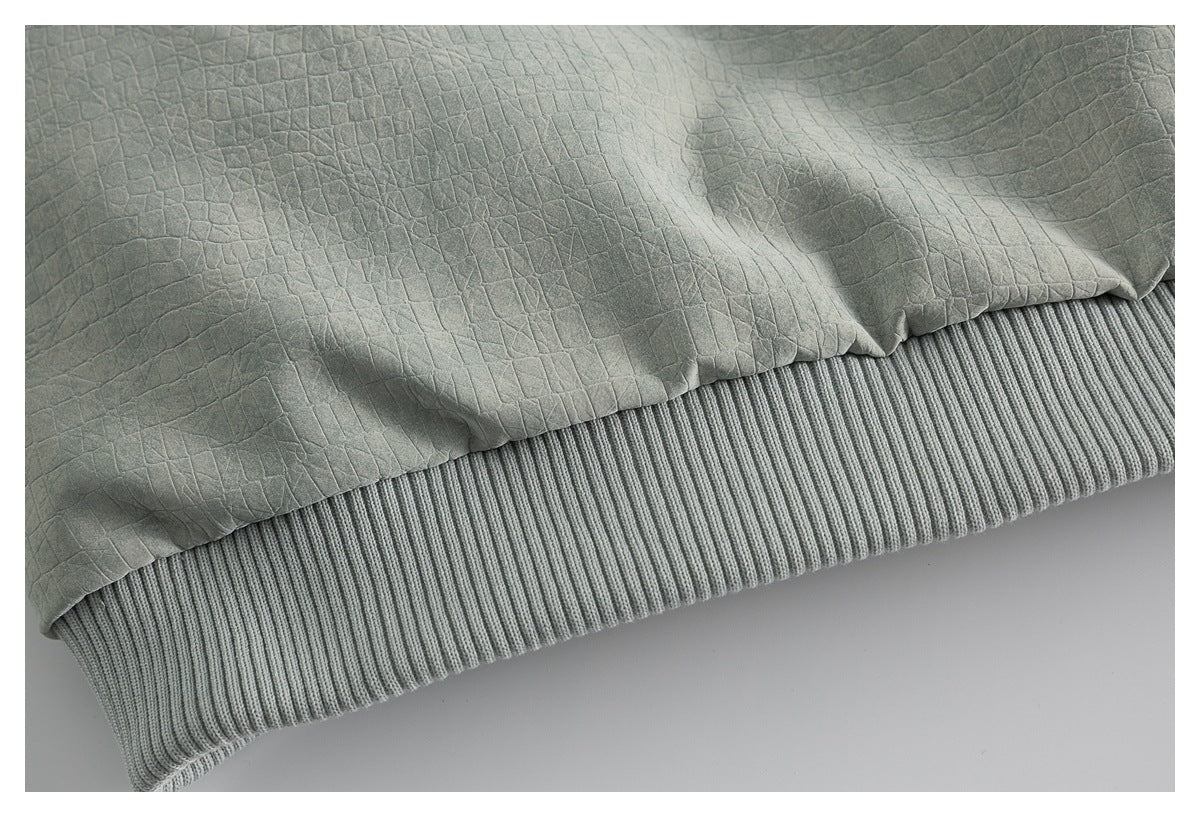 Close-up of sage-green textured fabric above a wide gray ribbed hem.