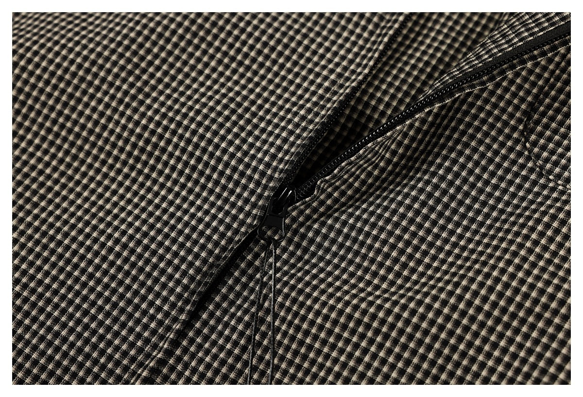 Close-up of a black zipper running through black and beige small-check garment fabric.