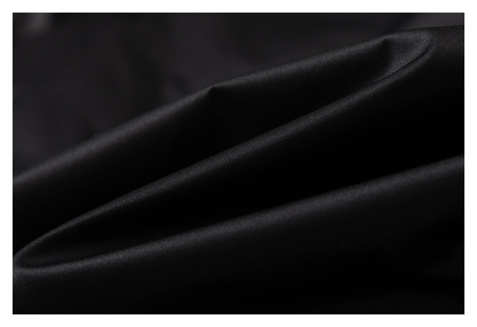 Extreme close-up of smooth black garment fabric arranged in soft folds.
