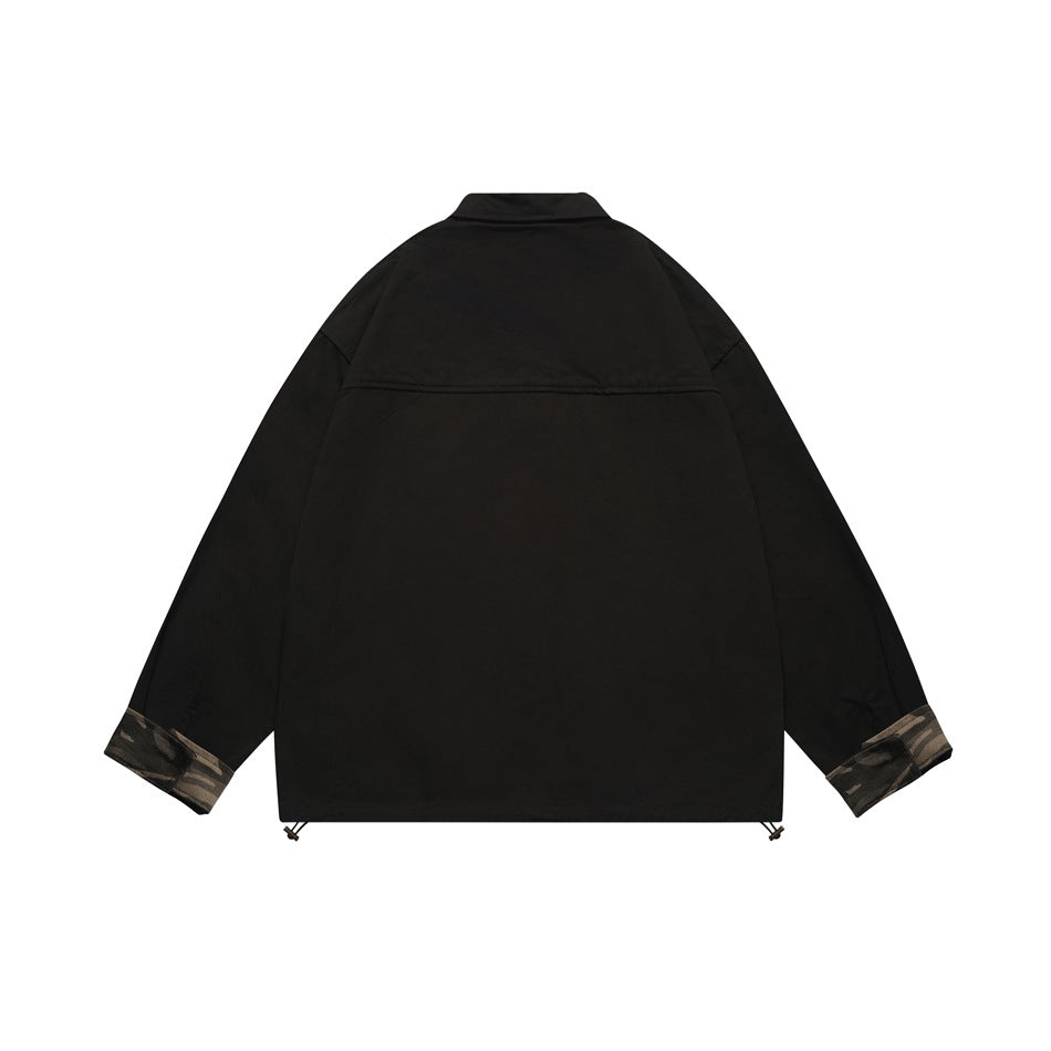 Back view of a black long-sleeve collared top with camouflage-patterned cuffs and a horizontal upper-back seam.
