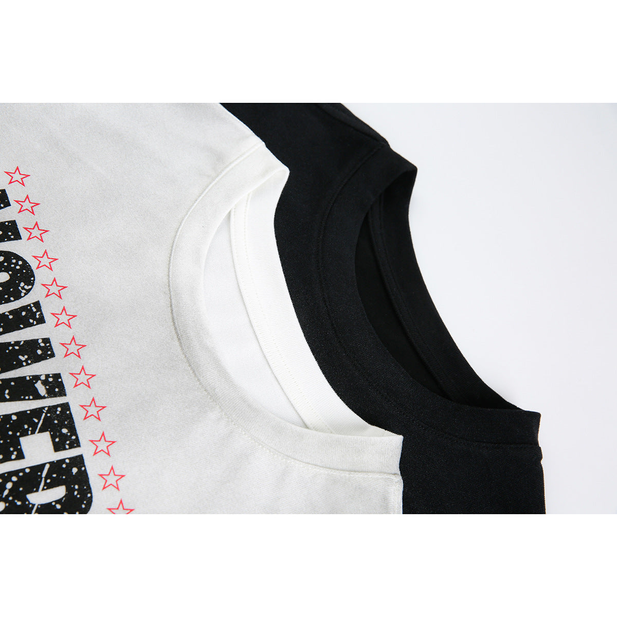 Close-up of white and black long-sleeve shirts showing their crew necklines and part of the printed design.