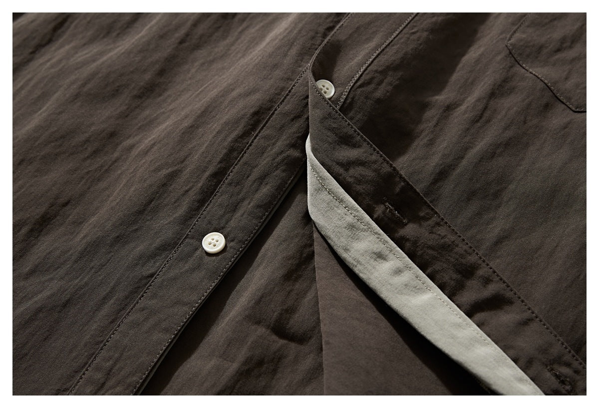 Close-up of a dark brown shirt placket opened to show its gray-green underside and white buttons.