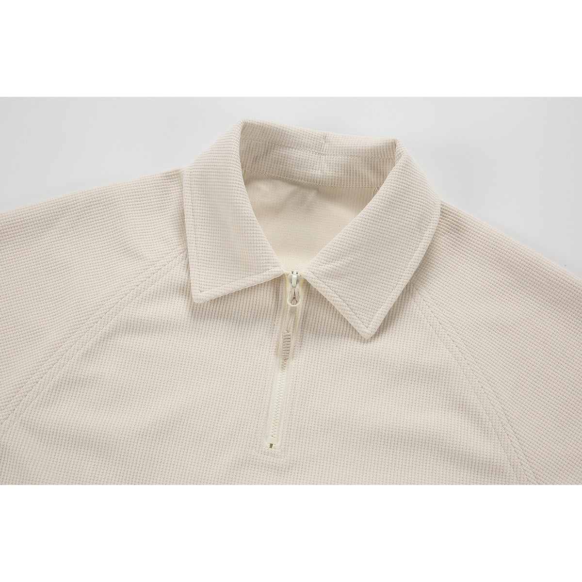 Close-up of a cream textured pullover's pointed collar and short front zipper.