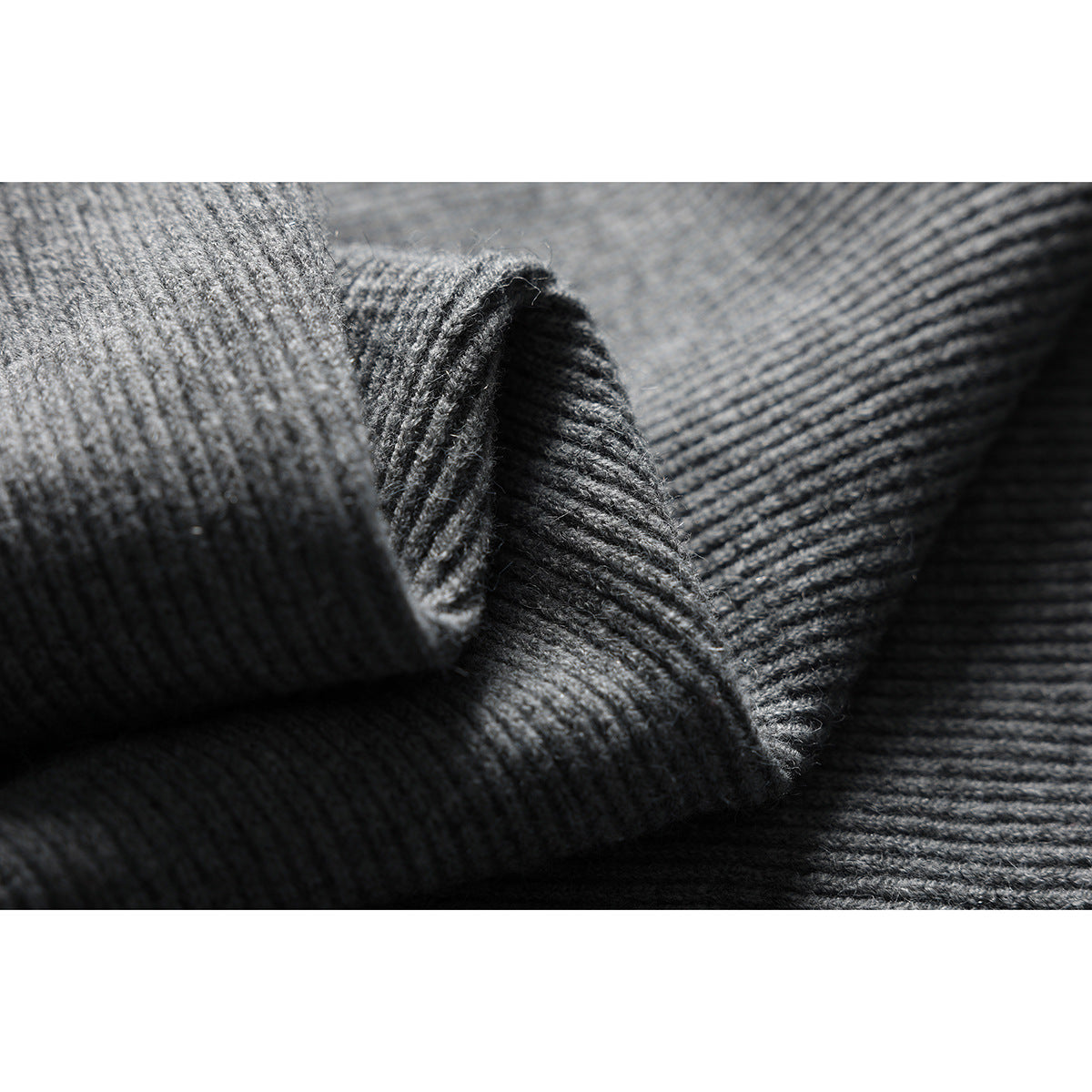 Close-up of charcoal gray rib-knit sweater fabric folded to show its texture.