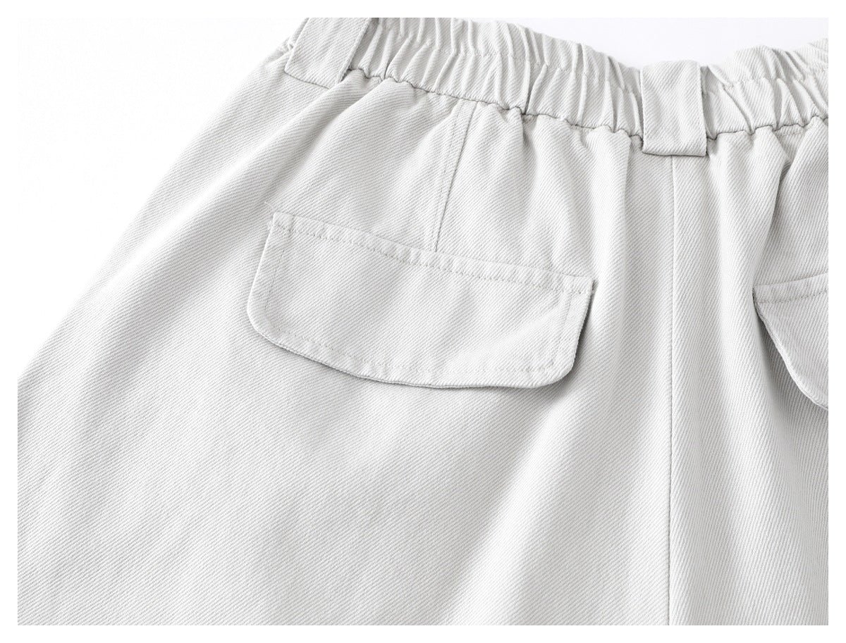 Close-up of a patch pocket, belt loop, and elasticated waistband on light gray trousers.