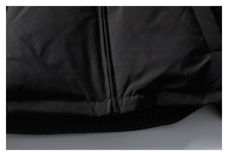 Close-up of a black garment hem with a stitched seam and dark plaid lining visible underneath.