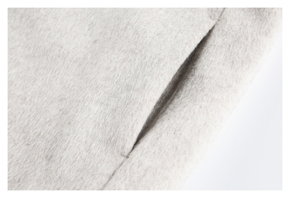 Close-up of a seam and folded edge on cream coat fabric.