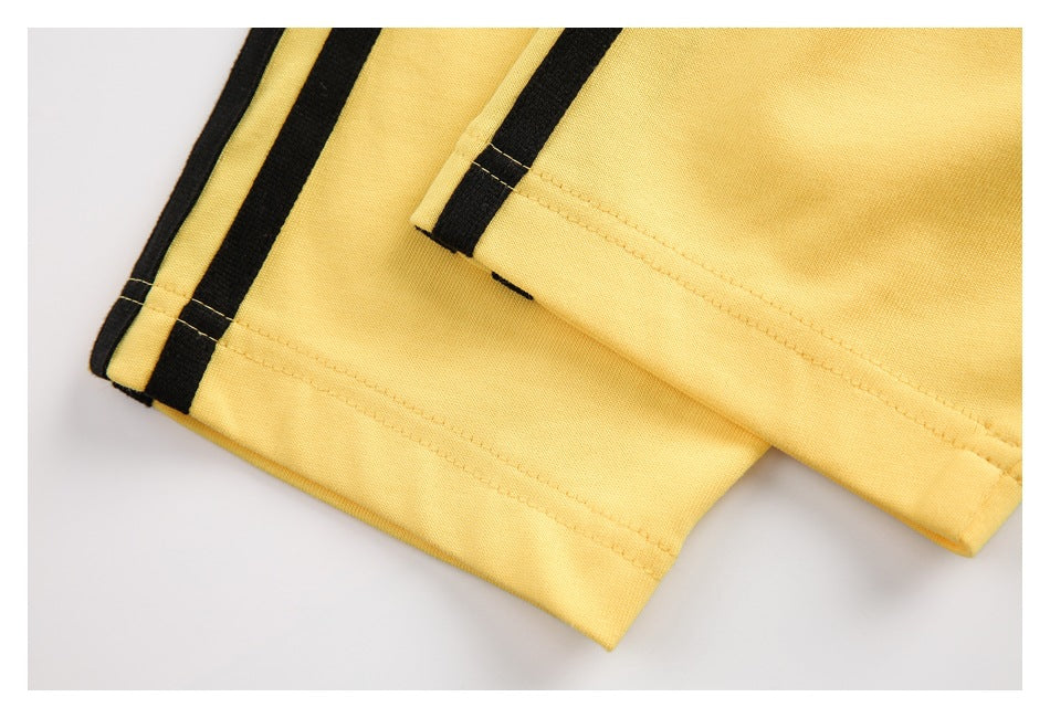 Close-up of yellow garment hems with black stripe trim and visible stitching.