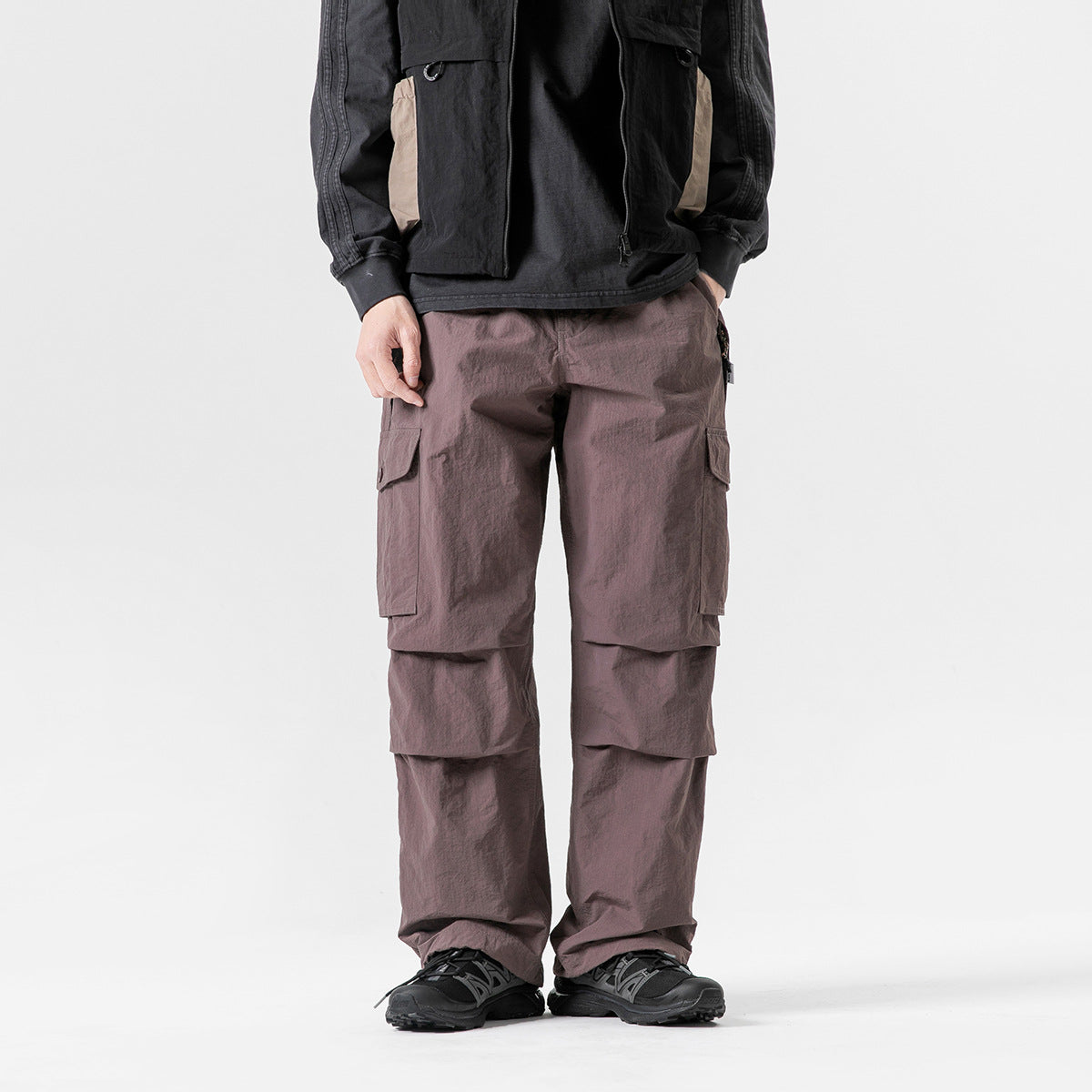 Model wearing muted mauve cargo pants with large side pockets and layered knee panels, shown from the front.
