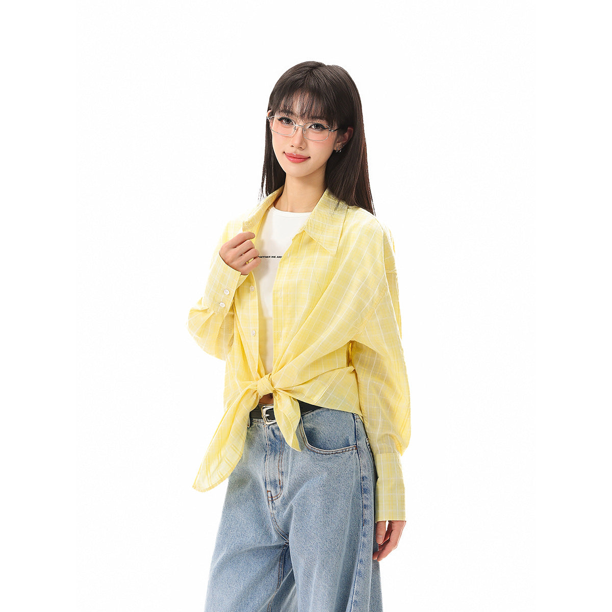 Model wearing a yellow windowpane-check shirt tied at the waist over a white top and loose blue jeans.