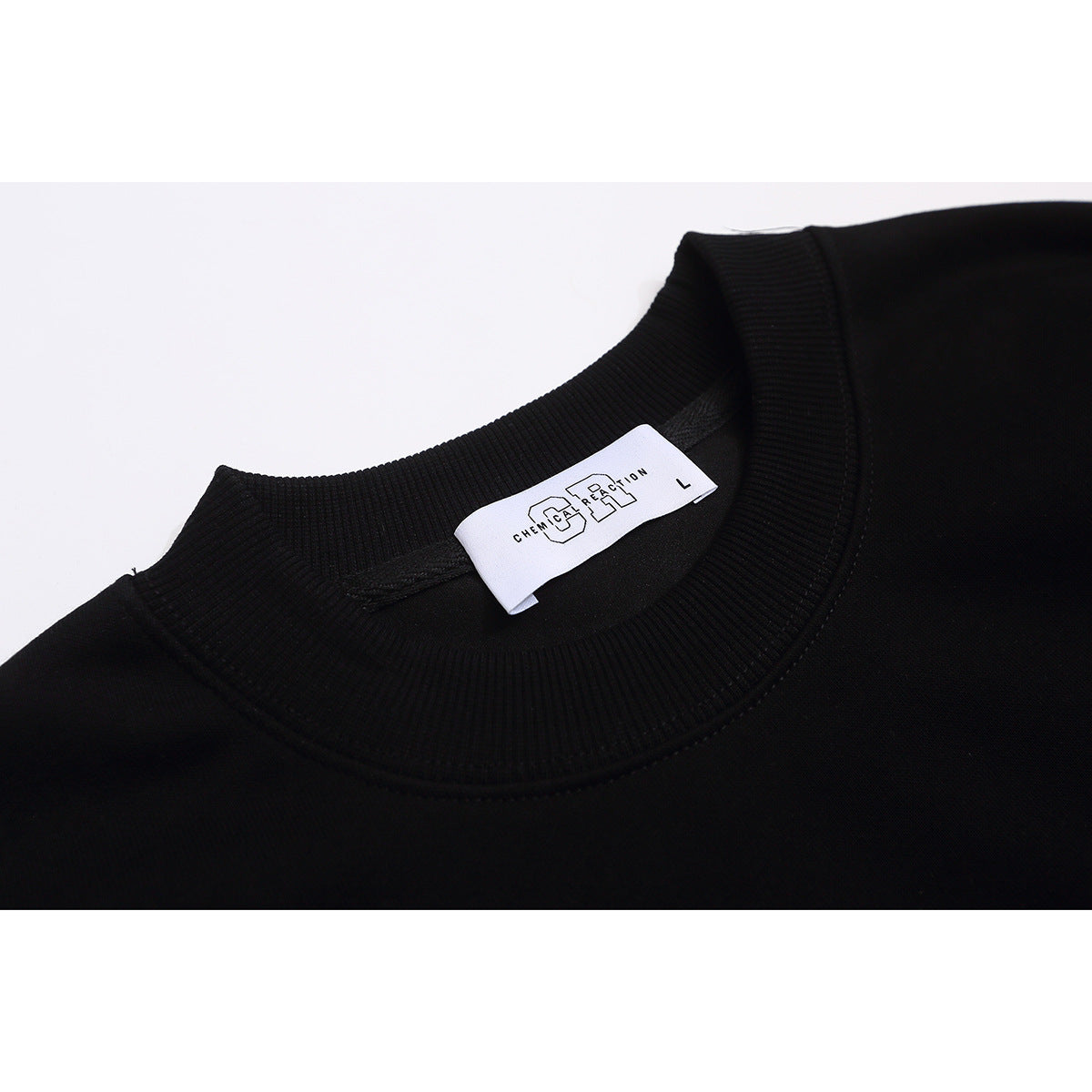 Close-up of a black sweatshirt’s ribbed crew neck and sewn neck label.