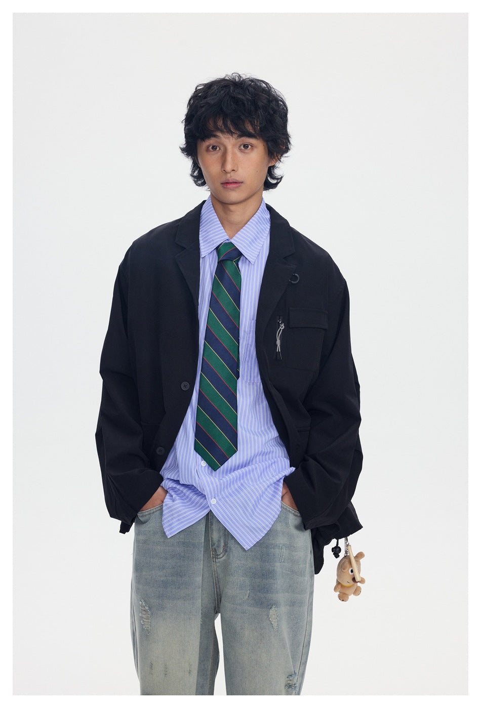 Closer front view of a model wearing a black blazer over a blue striped shirt and green striped tie.