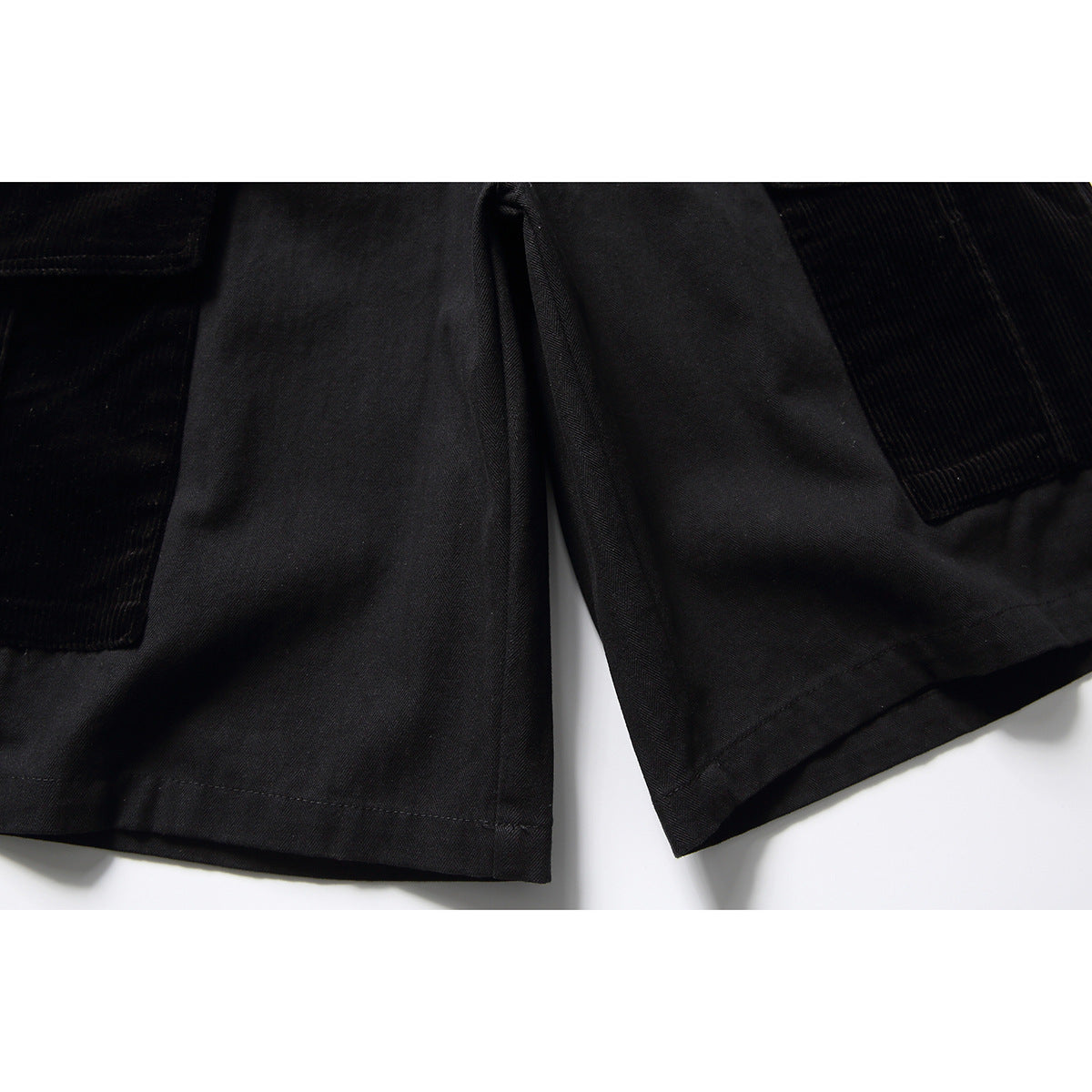 Close-up of black cargo shorts showing the legs, hems, and textured pocket panels.