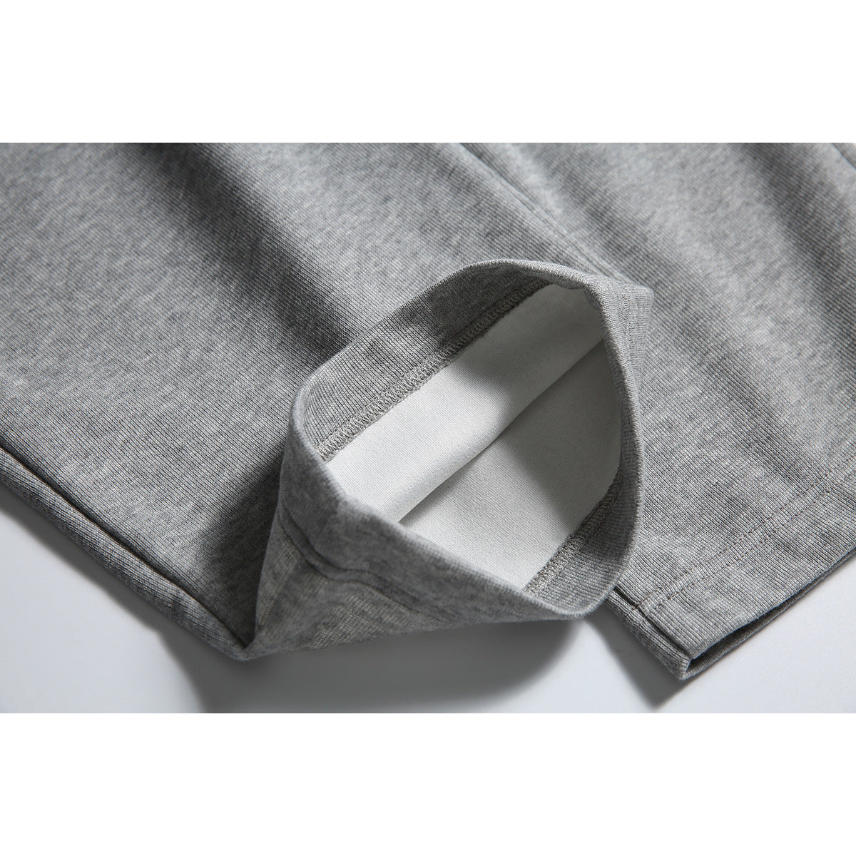 Close-up of a heather gray sweatpants leg hem folded open to show the inside and stitching.