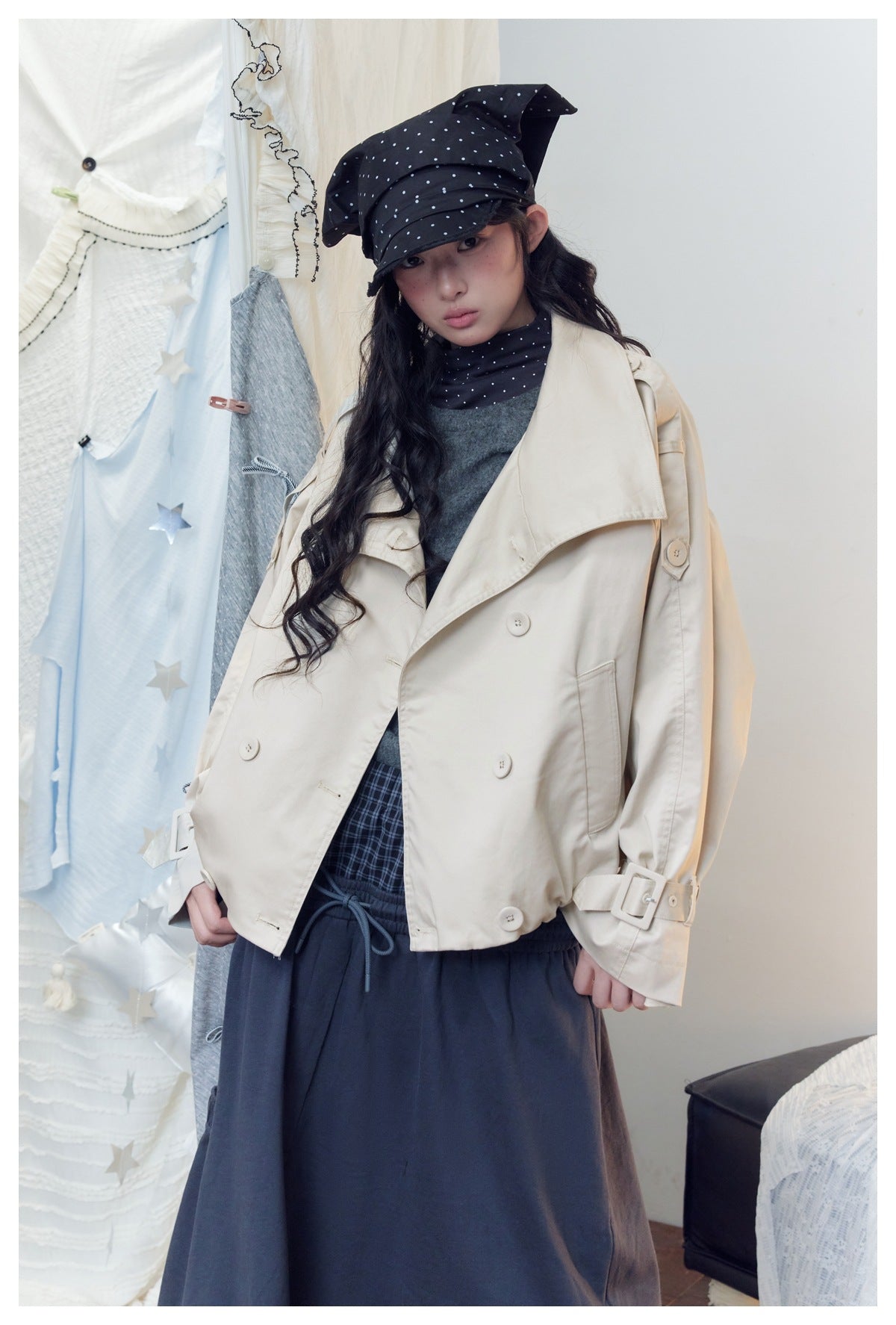 Model wearing a cream double-breasted jacket with broad lapels, buttoned cuffs and adjustable sleeve straps.