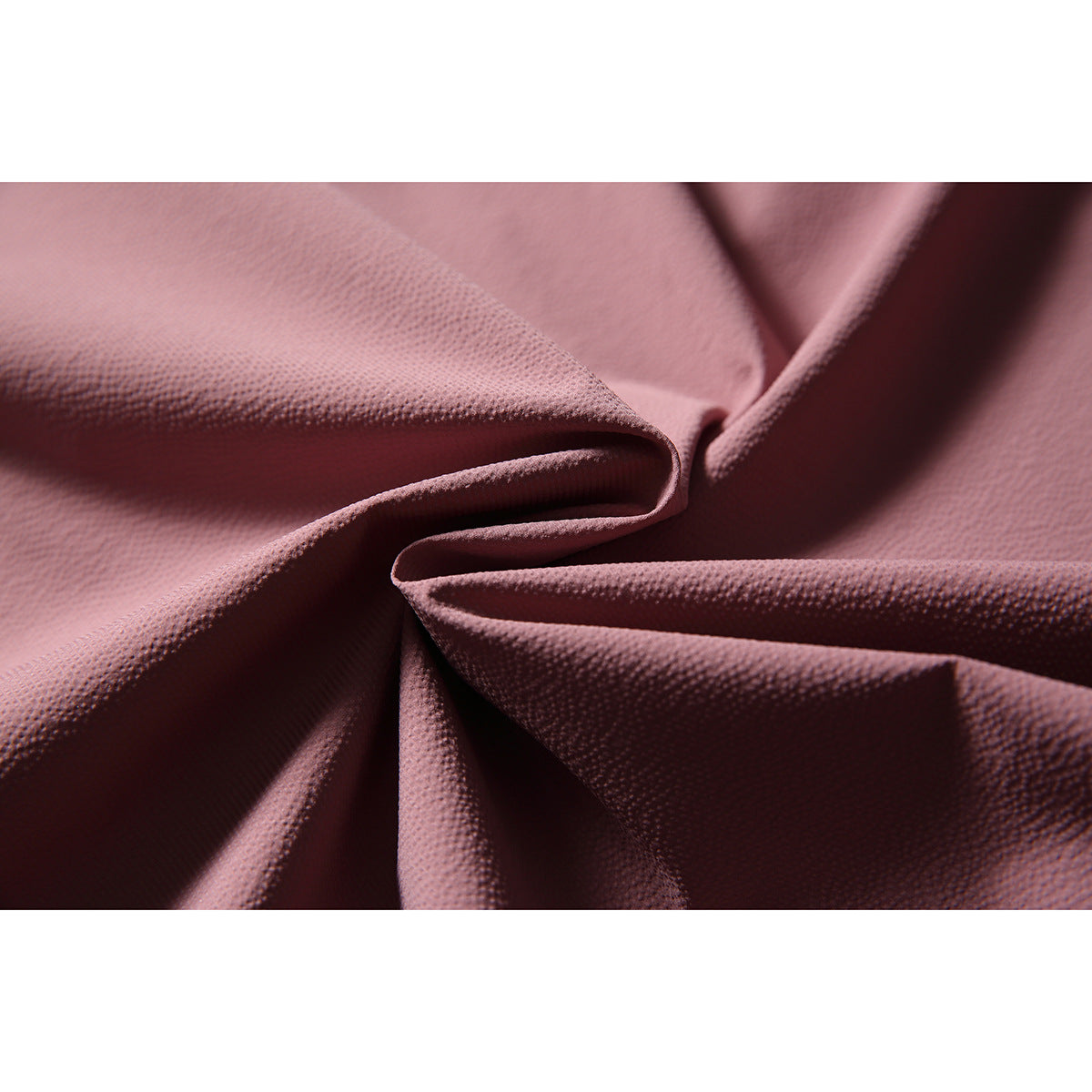 Macro view of the dusty rose vest fabric gathered into folds, showing its fine surface texture.