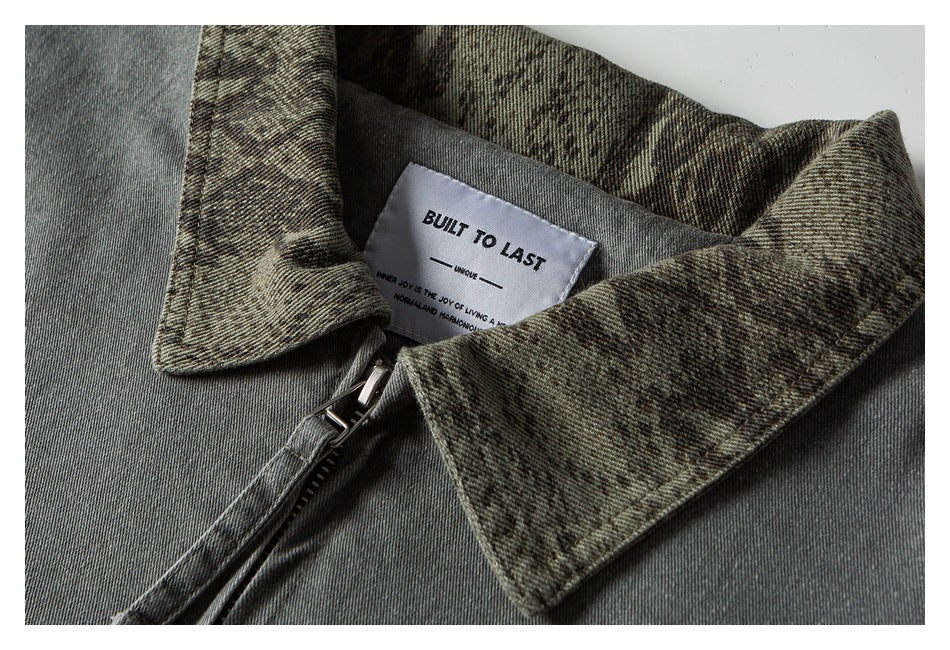 Close-up of a gray jacket collar with mottled olive lining, a front zipper, and a sewn-in label.