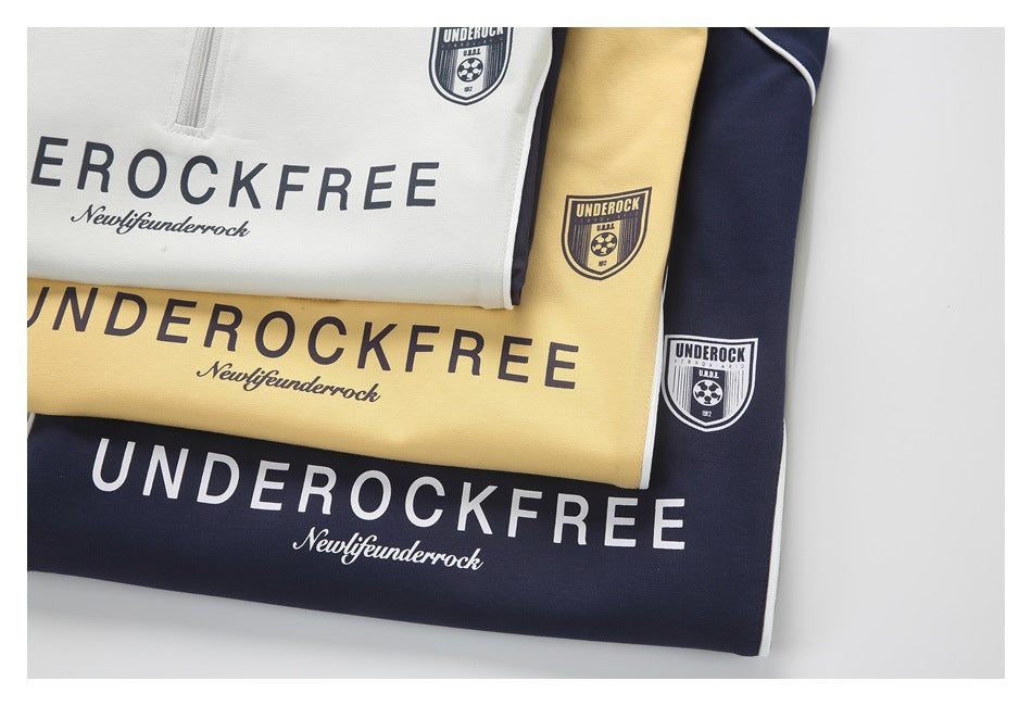 Folded white, pale yellow, and navy tops with printed lettering, shield emblems, and white piping.