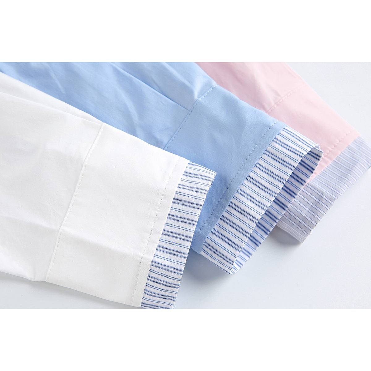 Close-up of striped inner cuffs on white, light blue, and pink shirts.