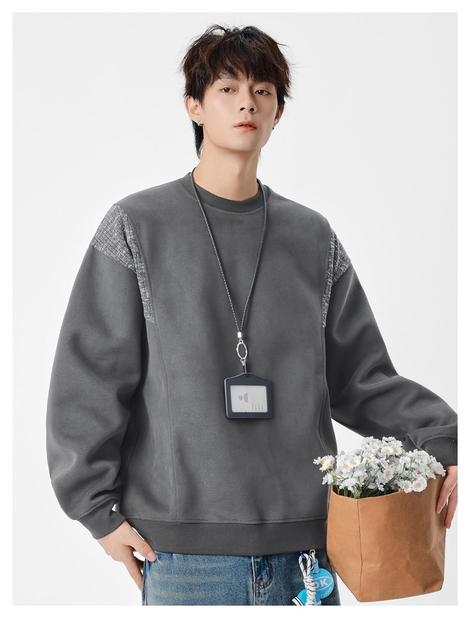 Model wearing dark gray crew-neck sweatshirt with textured shoulder panels and ribbed hem, holding a flower bag