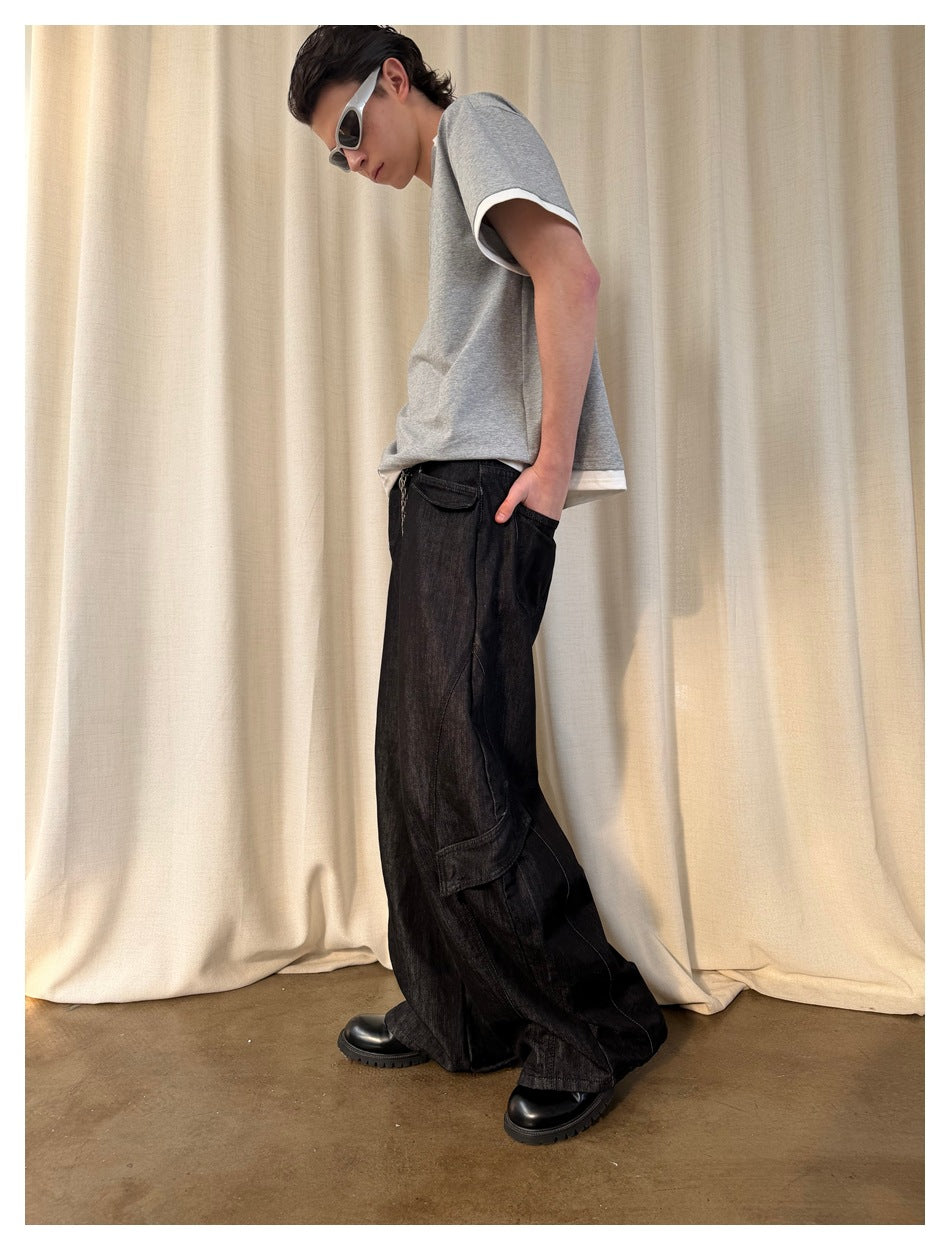 Side view of a model wearing a gray T-shirt with white trim and loose black cargo jeans.