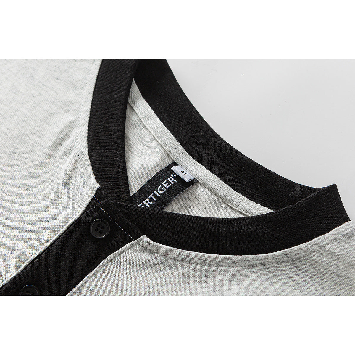 Close-up of a heather-gray shirt collar with black ribbed trim, button placket, and a woven neck label.