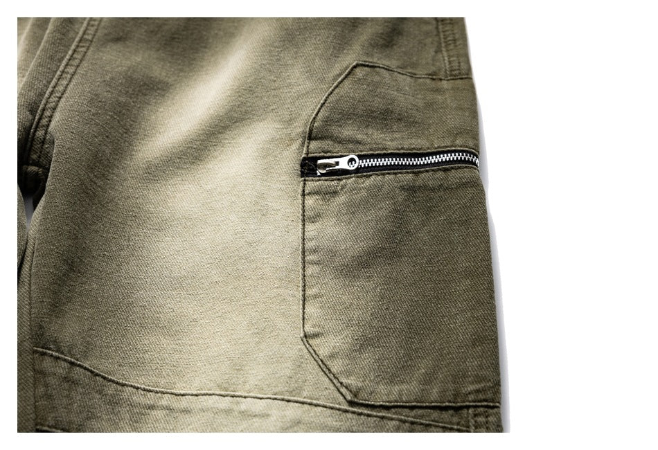 Close-up of an olive trouser leg pocket with a horizontal black zipper and stitched panels.